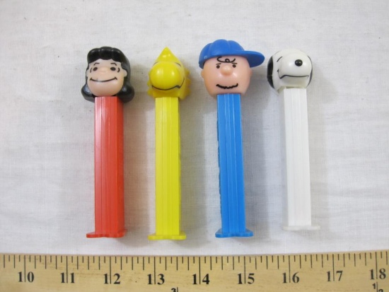 Four Vintage Peanuts PEZ Dispensers including Snoopy, Woodstock, Lucy, and Charlie Brown, all marked