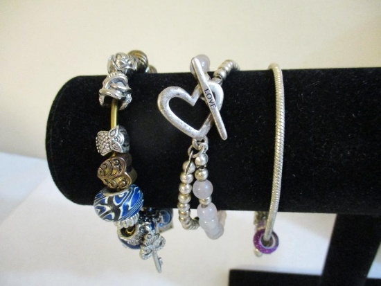 Three Silver Tone Bracelets including two-strand with beads, charms and more, 3 oz