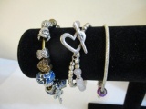 Three Silver Tone Bracelets including two-strand with beads, charms and more, 3 oz
