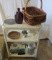 3 Shelf Cart with items on it. Purple bottle, basket, metal trivet, wooden decorative plate, coffee