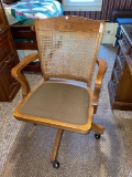 Wooden wickered-back swivel desk chair on rollers