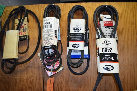 ASSORTED V-BELTS HANGING ON BACK OF BENCH