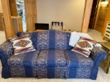 Three seater blue couch with two pillows and a throw