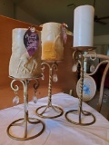 Trio of cast metal graduated, dangle gem candle holders with candles