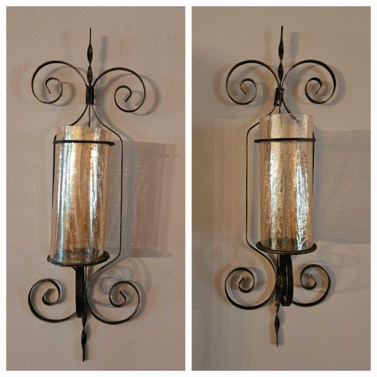 Matching pair of wrought metal wall sconces with glass candle guards
