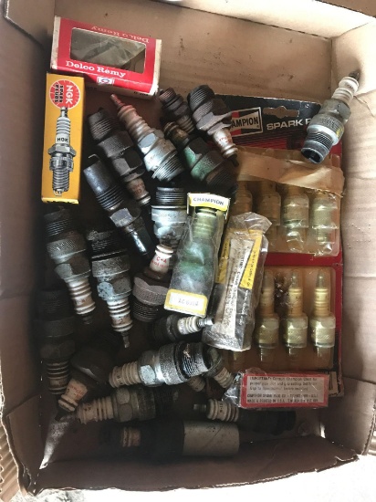 Assortment of new and used spark plugs, mostly for John Deere tractors.