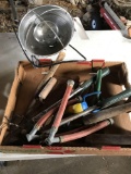 Box of garden tools, pruners, cement trowel, grass snipper, and heat lamp.