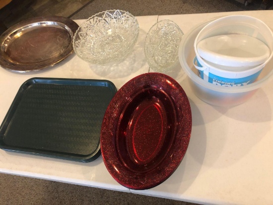 Plastic serving trays, oval plastic salad bowls, glass serving bowls and Tupperware cake lid.