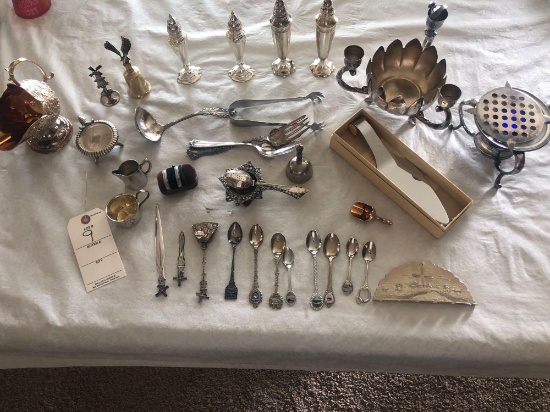 Silver spoons in holder, tea strainer, utensils, salt and peppers, candleholders, polish rag and