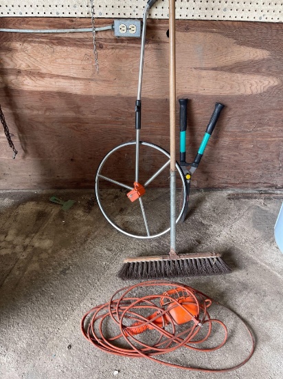 Measuring wheel, broom, trouble light, two handled trimmer.