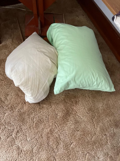 Wooden plant stand or shelving unit with two feather pillows.