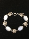 Oval 15x10mm White Cat's Eye Cabochon & Angelfish Charm Accented 7in Long Sterling Silver Bracelet