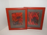 two prints of vibrant red flowers also framed in red -