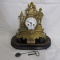 French ormolu clock w/ embossed cherub face and man standing on rock. 13 x