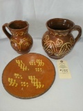 TWO HANDLED REDWARE POTTERY DECORATED PITCHERS AND REDWARE DECORATED PLATE