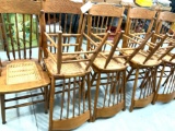 Nine pressed back oak chairs with wood cock design, spindle backs, cane seat