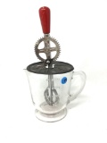 Clear antique beater jar with a red handle handle