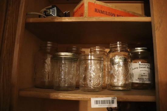 Contents of cabinet of ball and mason jars including measuring cups, etc.