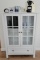 White cabinet w Keurig an Nespresso machines. Items from Holland
