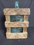 Wood crate with glass 4 gallon water jug inside.