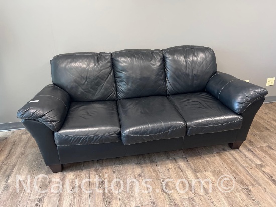 black leather three-seater sofa with rounded padded arms