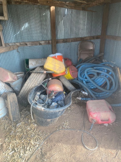 Shed full of miscellaneous stuff gas cans propane tanks couple tires Seed spreader water can And