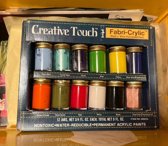 Storage container with artist pints and paper, clips, and various other items in the in the