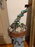 Fountain where water trickles down from the top to the bottom where a bed of rocks are