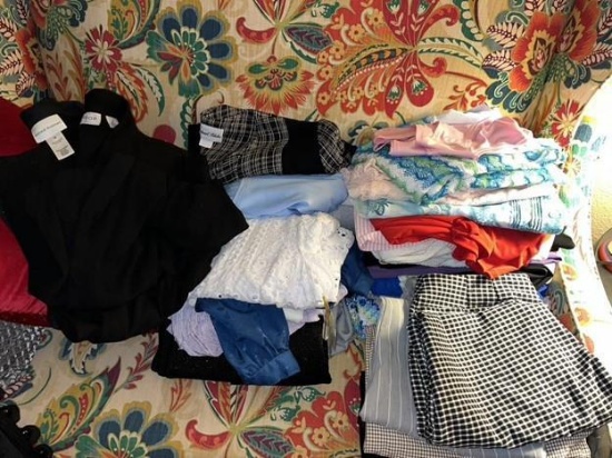 Storage basket and bags of women's blouses and pants, mostly large and extra large with a few