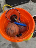 Basketballs, softballs,racket, golf balls in orange bucket