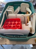 Green tote with plastic shower caddy, plastic egg holders, plastic serving dishes, plastic fruit