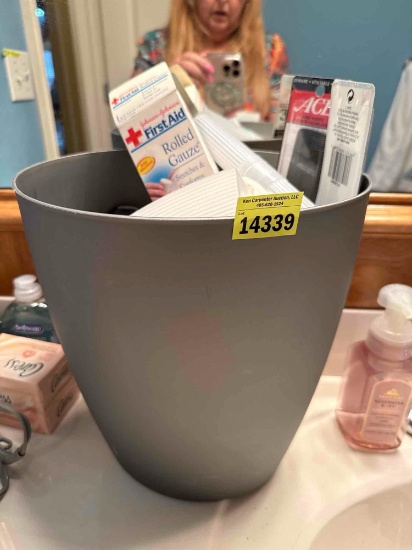 Wastebasket, full of first aid items, soap, comb, and more