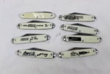 Eight Coca-Cola advertising knives with 2.5 inch single blades and white scales.