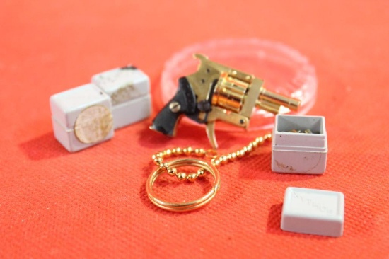 Gold colored very small revolver keychain. With three boxes of very small blanks.