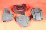 Three black plastic holsters. Two right handed, one belt and one paddle, one left handed belt clip