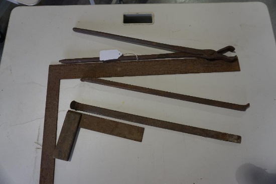 One framing square, small wood and metal square, blacksmith's tongs, and metal pry bar.