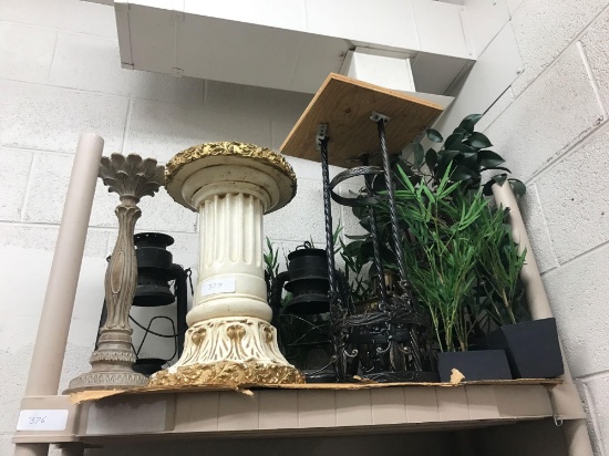 Shelf of candle stick holders fake plants and vintage lanterns