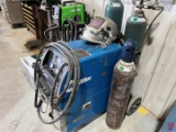 MILLER MILLERMATIC 350 WIRE WELDER W/ WELDING HELMENT, STRIKERS,  3-COMPRESSED GAS BOTTLES, & ROLLIN