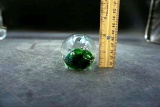 Round glass paperweight with green.