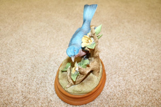 Porcelain piece of bird on its perch with wood plank