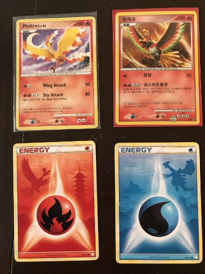4 Pokemon Cards Moltres Level 42 Card Ho-Oh 2 Energy Cards with Pokemon Shadows in the Background