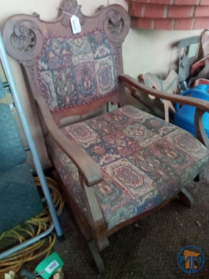 Upholstered rocking chair and wall hangings: metal peacocks, wood leaf wreath, spoon