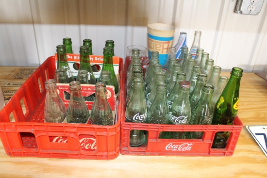 (2) plastic bottle crates with various glass bottles in holders, mugs, and