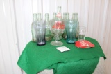 (9) Coca Cola glass bottles and (4) assorted glasses, (4) coasters