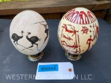 2 painted Ostrich Eggs, - African Hunting & Battle Scenes on display stands 7 1/2 inches tall x 4 1/