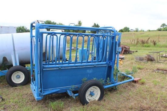 Blue portable livestock squeeze chute with wheels and headgate