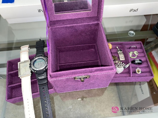 In office, purple jewelry box with rings, pins, watches.