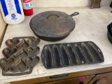 Cast iron pan and two cast iron molds In a rec room