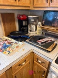 Right side of the sink contents on countertop cutting boards coffee pots and other