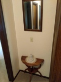 Wooden stand, mirror and figurine at end of hallway